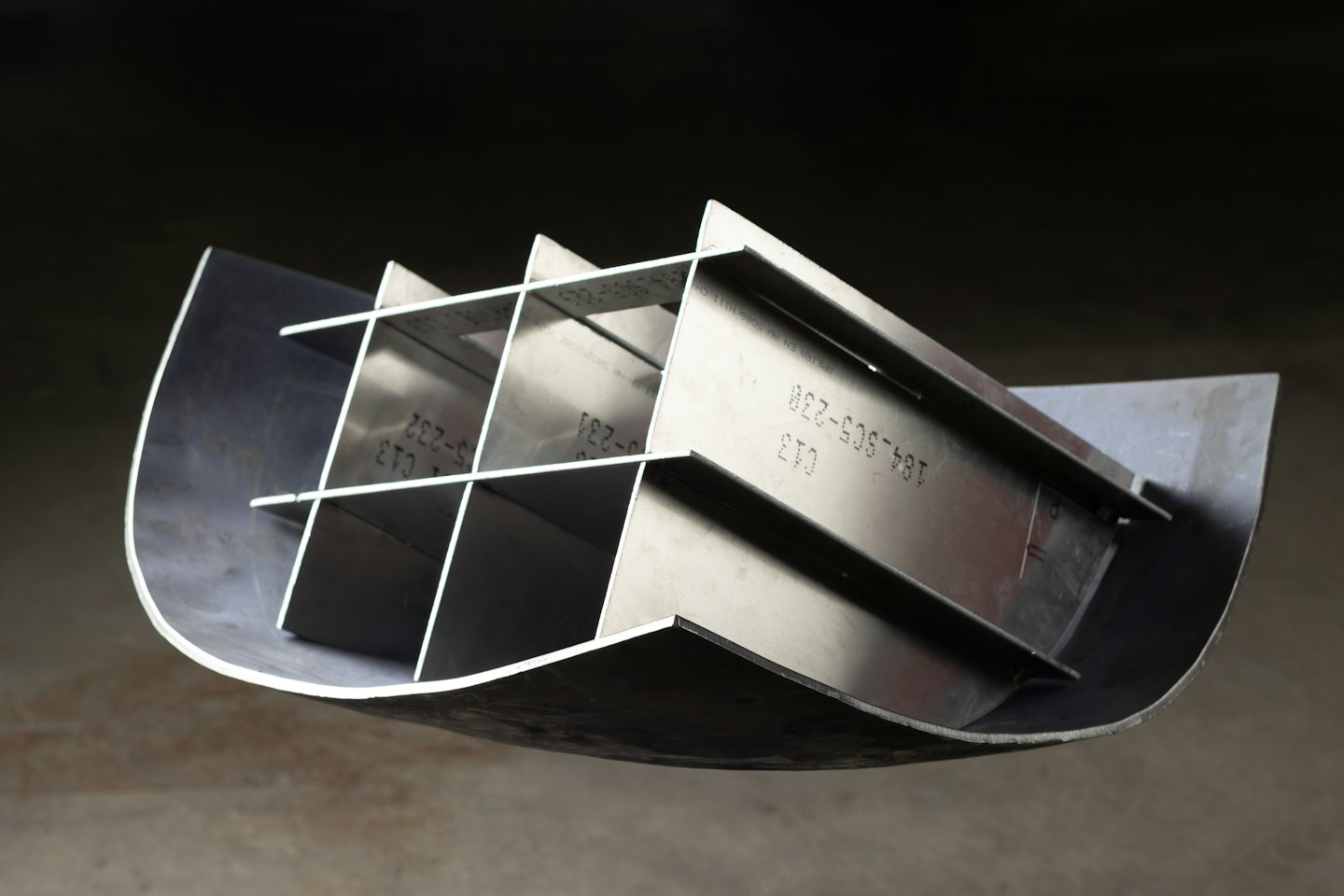 Metal industrial component featuring internal fins and serial numbers.