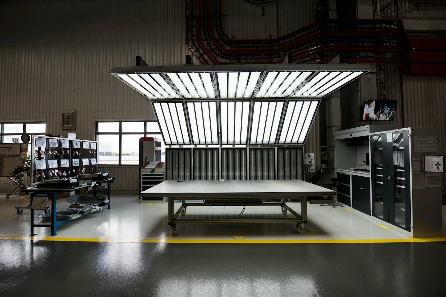 Empty industrial assembly station with tools and inspection table.