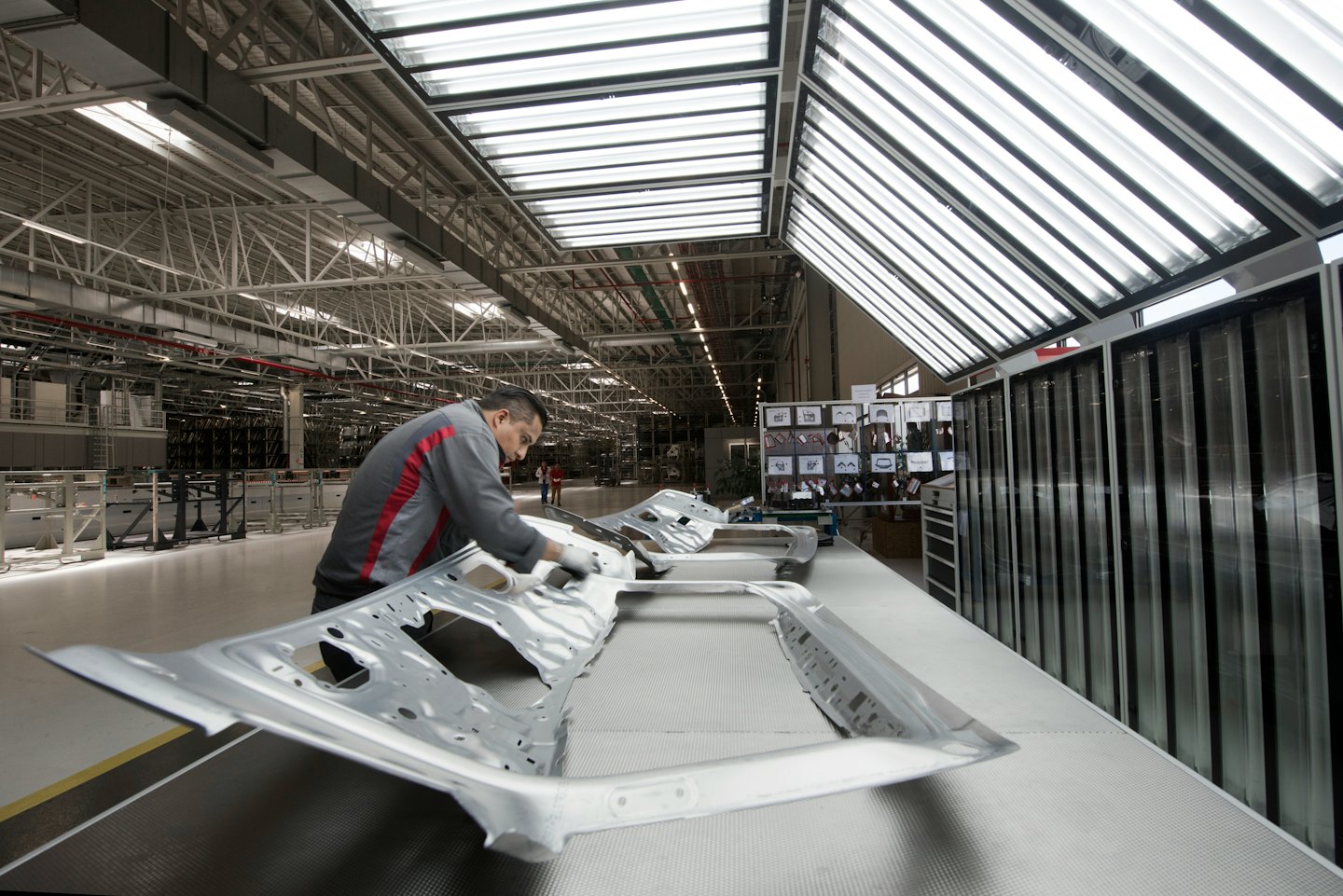 Man inspects car frame on factory production line.